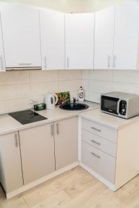 a kitchen with white cabinets and a microwave at Апартаменты Красная, 10Б in Kemerovo