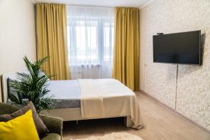 a hotel room with a bed and a flat screen tv at Апартаменты Красная, 10Б in Kemerovo