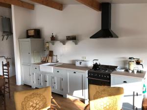 uma cozinha com armários brancos e um forno com placa de fogão em Halte Bontebrug em Silvolde