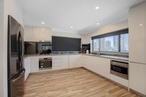 a kitchen with white cabinets and a large window at 29 Stanhill drive in Gold Coast