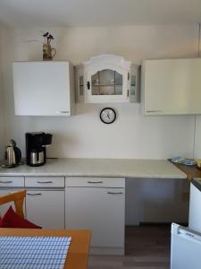 una cocina con armarios blancos y un reloj en la pared en Ferienwohnung Kraihof, 83703 Gmund am Tegernsee, en Gmund am Tegernsee