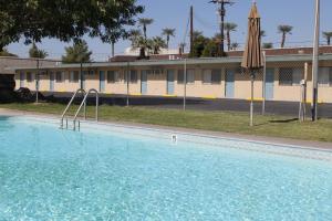 einem großen Pool mit Sonnenschirm und einem Gebäude in der Unterkunft Indio Holiday Motel in Indio
