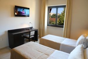 um quarto de hotel com duas camas e uma secretária e uma televisão em Albergo Cantiani em Ancona