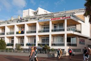 un edificio blanco con gente caminando delante de él en Marsin Playa 408 Vivienda vacacional, en Las Palmas de Gran Canaria