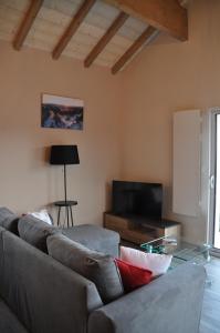 a living room with a couch and a tv at les charmes du lac Sauna et Spa in Gérardmer