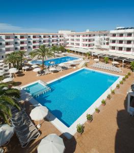 vista aerea su una piscina del resort con ombrelloni di Coral Star Hotel a Baia di Sant'Antoni