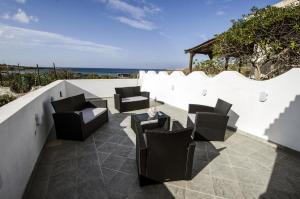 a patio with chairs and a table and the ocean at A.I.R. Villa Marinedda in Isola Rossa