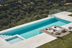 an overhead view of a swimming pool with two people sitting on a couch in front at Villa Niolos II in Stérnai