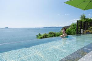 una mujer en una piscina al lado del agua en Miyahama Grand Hotel, en Hatsukaichi