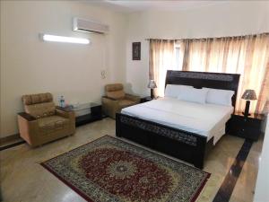 a bedroom with a bed and a couch and a chair at Melberry House in Islamabad