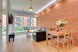 a living room with a table and a brick wall at Central Apartment - free private parking in Gdańsk