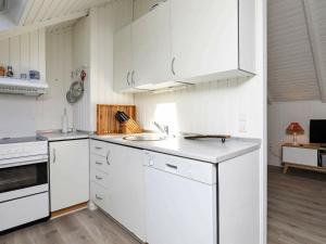 a white kitchen with white cabinets and a sink at 6 person holiday home in L s in Læsø