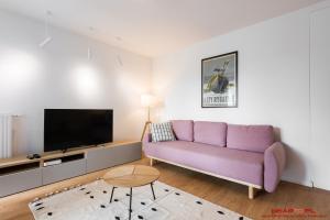 a living room with a purple couch and a tv at Apartments Nearto Old Town Vermelo in Krakow