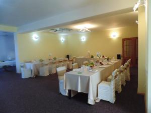 una habitación con mesas y sillas con manteles blancos en Pensiunea Casa Benko, en Bacău