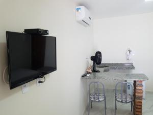 een flatscreen-tv hangend aan een muur met twee barkrukken bij Pousada Areal Barra Grande Maragogi AL in Maragogi