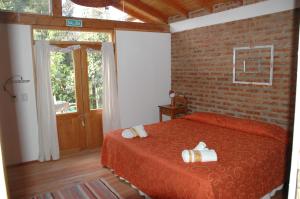 a bedroom with a red bed and a brick wall at Cabaña Accesible Ipua in Lago Puelo