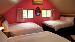 two beds in a room with red walls and windows at Goose House in Yung-an-ts'un