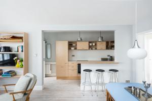 a kitchen with white walls and bar stools at Seahorse Cottage in Aldeburgh