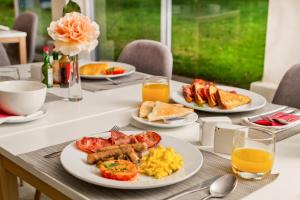 stół śniadaniowy z talerzami jedzenia i sokiem pomarańczowym w obiekcie The Pecan Tree Guesthouse w mieście Johannesburg