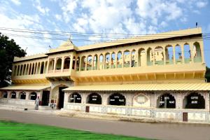 a large yellow building with windows and a person standing in front at Hotel Shahi Palace Mandawa in Mandāwa