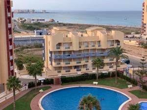 a building with a swimming pool in front of a beach at Penthouse Los Miradores del Puerto in La Manga del Mar Menor