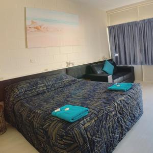 a hotel room with a bed and a chair at Tropical City Motor Inn in Ayr