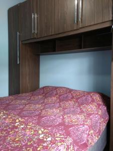sypialnia z fioletowym łóżkiem i drewnianymi szafkami w obiekcie Casa em condomínio a 150 m da praia w mieście Bertioga