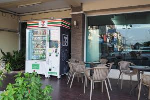 a restaurant with tables and chairs in front of a refrigerator at Phromsuk Hotel Ayutthaya in Phra Nakhon Si Ayutthaya