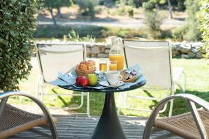 ein Tablett mit Frühstückszutaten auf einem Tisch mit Stühlen in der Unterkunft Hotel Le Phoebus Garden & Spa in Gruissan