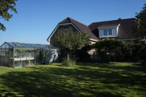 una casa con un patio verde con un invernadero en Groot familiehuis voor 6 personen in landelijke, rustige omgeving, en Breezand