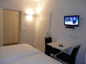 a room with a bed and a table and a tv at Astra Hotel in Kaiserslautern