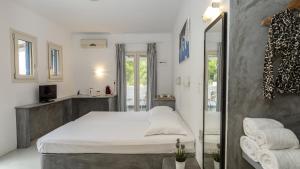 a bedroom with a large white bed and a mirror at Coralli Seaside Resort in Livadakia
