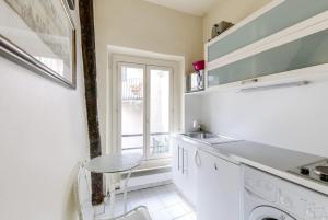 a white kitchen with a table and a window at Unit 015 Notre Dame (Ursins n°2) in Paris