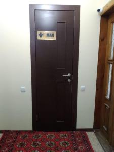 Una puerta marrón con un cartel de hombre. en Samia House Room on Furkat 8, en Tashkent