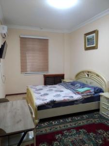 een slaapkamer met een bed, een tafel en een raam bij Samia House Room on Furkat 8 in Tasjkent
