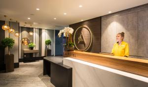 a woman sitting at a counter in a hotel lobby at Aerotel London Heathrow Airport, Terminal 2 & Terminal 3 in Hillingdon
