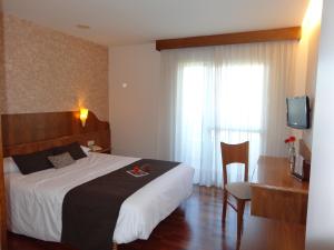 a hotel room with a bed and a desk and a television at Hotel El Pescador in Perillo