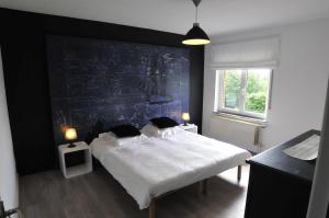 a bedroom with a large bed with a black wall at La Maison Des Artistes in Durbuy