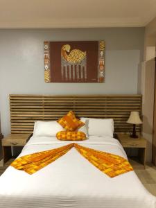 1 dormitorio con 1 cama blanca grande con mantas de naranja en Central Hotel - OSU en Accra