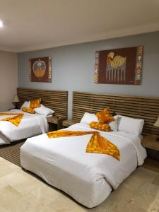 2 camas en una habitación de hotel con sábanas blancas en Central Hotel - OSU en Accra