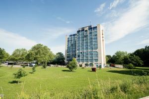 a large building in a park with a field at Carathotel Basel/Weil am Rhein in Weil am Rhein