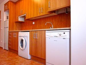 cocina con lavadora y armarios de madera en Apartamentos El Hortalán, en Mora de Rubielos