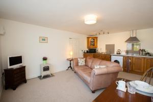 a living room with a couch and a kitchen at PERFECT BUSINESS ACCOMMODATION at SIDINGS FARM - Luxury Cottage Accommodation - Self Catering - Secure Parking - Fully equipped Kitchen - Towels & Linen included in Pidley