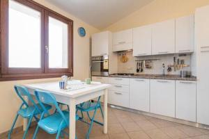 a kitchen with a white table and blue chairs at Nuovissimo Bilocale al Mare in Villa San Pietro