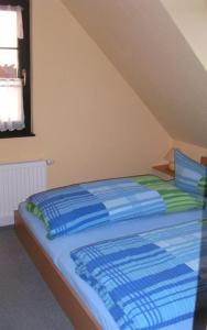 Bett mit blauer und grüner Bettwäsche in einem Zimmer in der Unterkunft Ferienwohnung Köhler in Glowe