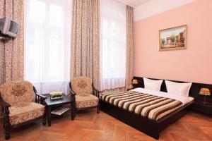 a bedroom with a bed and two chairs at Hotel-Pension Cortina in Berlin