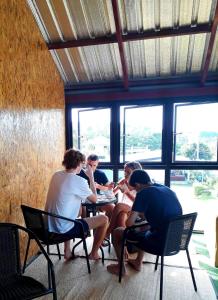 a group of people sitting at tables in a room with windows at Lanta Hostel in Ko Lanta