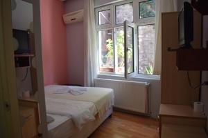 a small bedroom with a bed and two windows at Sur Istanbul Hotel in Istanbul