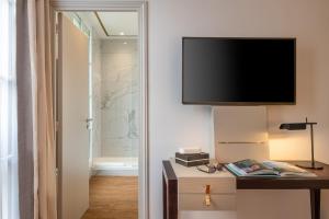 a room with a tv on the wall and a table with a desk sidx sidx at Hôtel Le Walt by Inwood Hotels in Paris