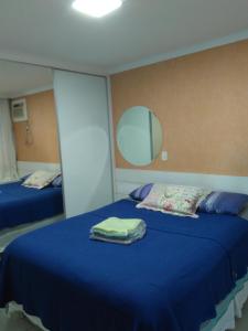 1 dormitorio con 2 camas con sábanas azules y espejo en D Frente Green D 2, en Vila Velha